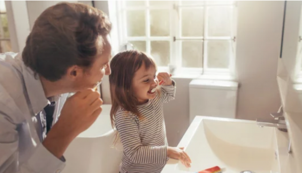 Pediatric oral health of a father brushing teeth with child