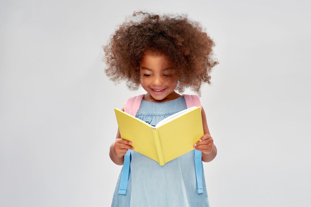 happy little african girl reading a book