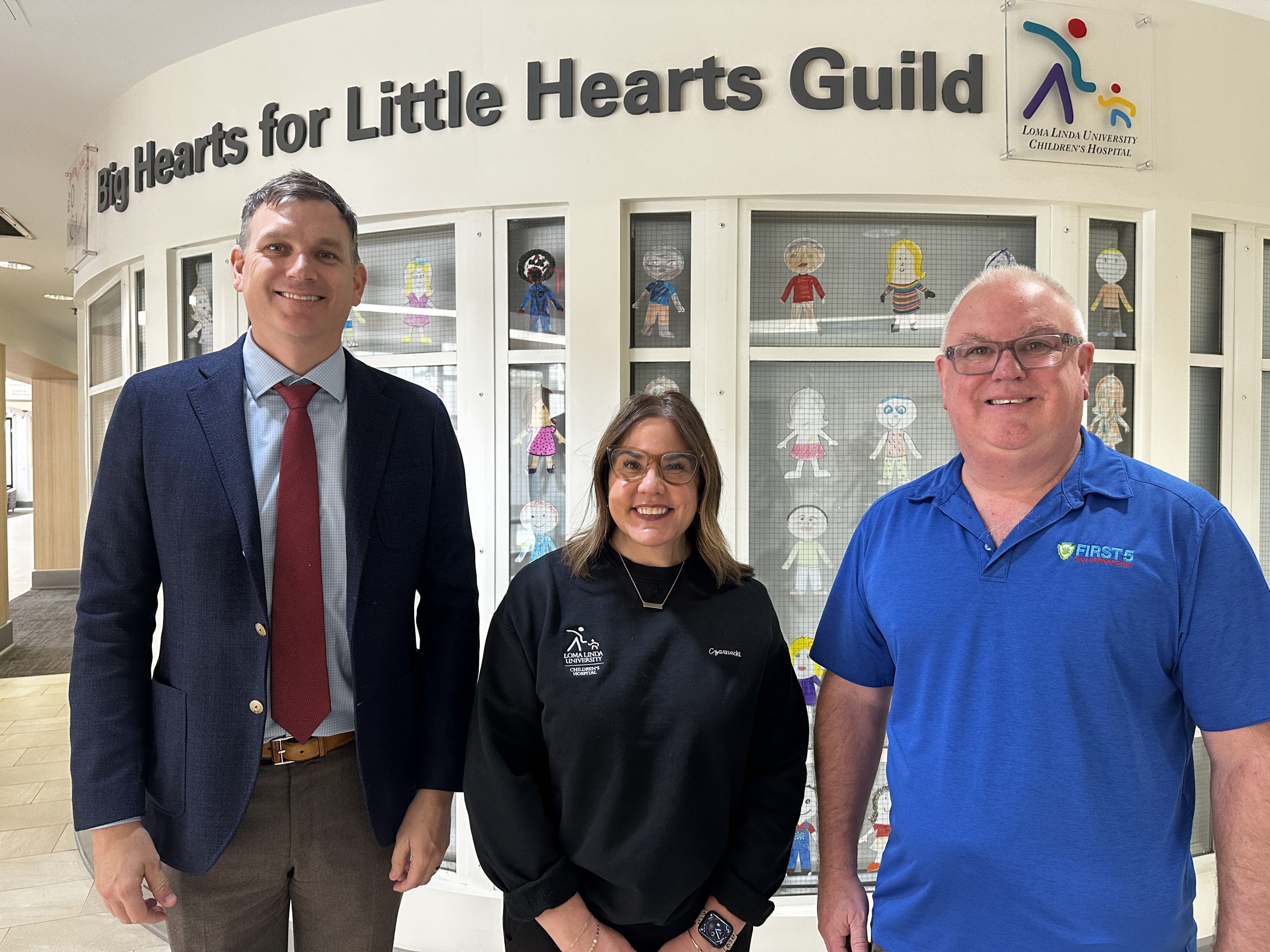 First 5 San Bernardino and Loma Linda University Children’s Hospital staff pose in front of a display of colorfully decorated paper dolls.