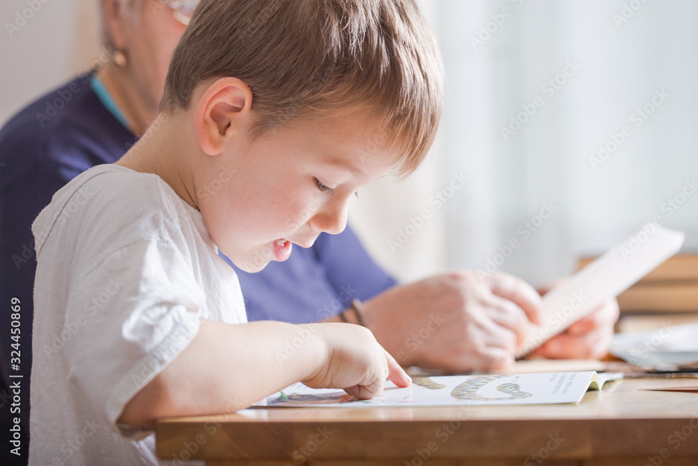 Little boy reading a book at the table.