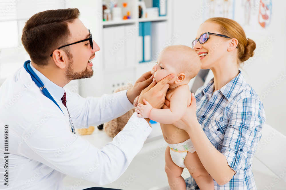 Baby being held up my mother while a dentist is looking in their mouth.